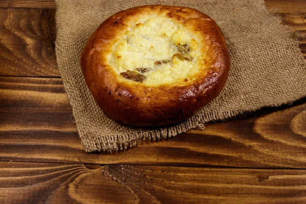 Zoete ronde broodje met kwark en rozijnen (Cheesecake) op houten tafel — Stockfoto