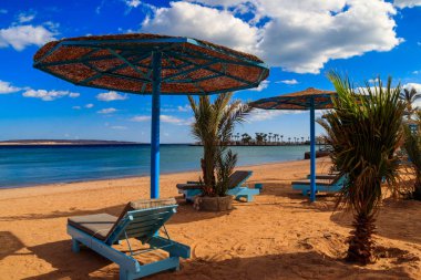 Tropik plajlarda güneş şemsiyeleri ve şezlonglar. Dinlenme, rahatlama, tatil, tatil