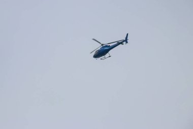 Mavi gökyüzünde uçan helikopter.