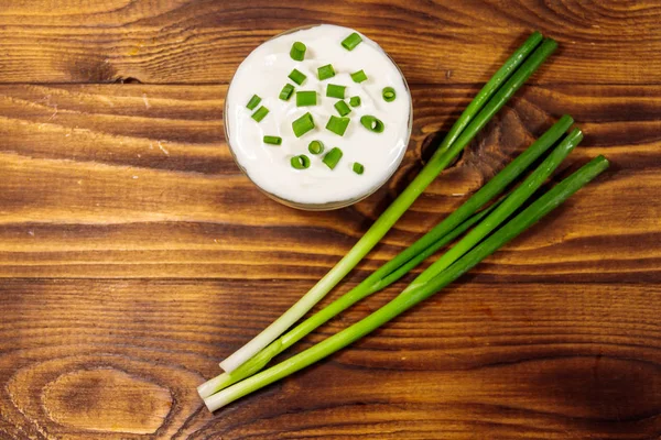 Sour cream and green onion on wooden table. Top view — Stock Photo, Image