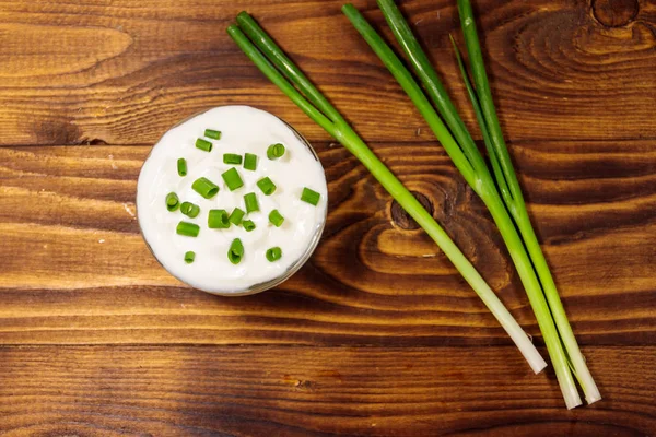 Sour cream and green onion on wooden table. Top view — Stock Photo, Image