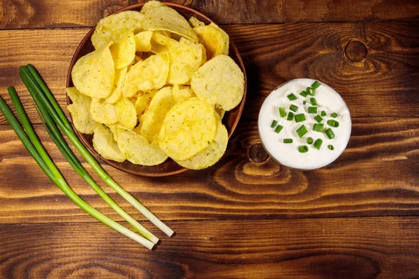 녹색 양파와 사 우 어 크림 나무 테이블에 싱 싱 감자 칩. 상위 뷰 — 스톡 사진