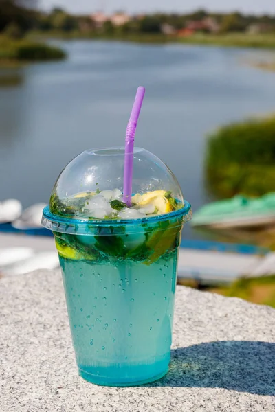 Mojito cocktail met citroen, ijs en bladeren van mint op een achtergrond van rivier — Stockfoto