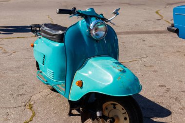 Şehrin caddesinde park etmiş mavi scooter.