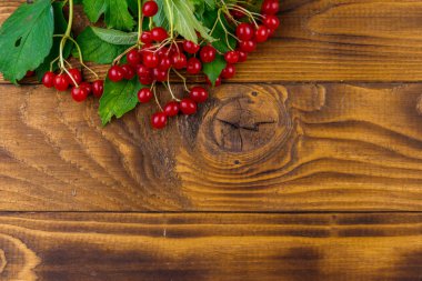 Ahşap masa üzerinde yeşil yaprakları ile kırmızı viburnum çilek. Üstte görüntü