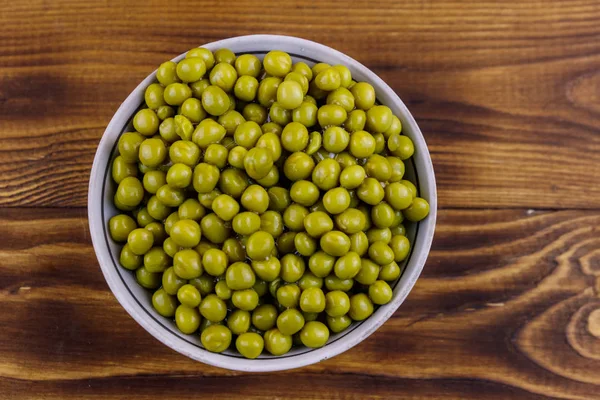 Bowl with canned green peas  on wooden table. Top view — Stock Photo, Image