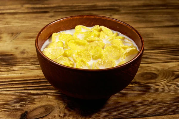 Flocos de milho com leite em uma tigela na mesa de madeira — Fotografia de Stock