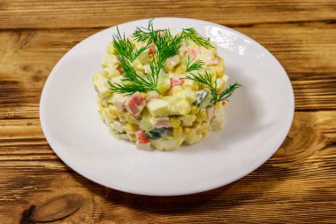 Yengeç çubuklu salata, tatlı mısır, salatalık, yumurta ve mayonez ahşap masada.