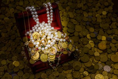 Altın sikke ve mücevherlerle dolu eski bir hazine sandığı.