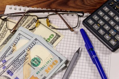 Defter ile dolar, kalem, gözlük ve ahşap masa hesap makinesi. Mali kavramı. İş rapor