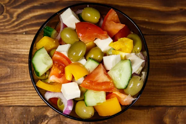 Salada grega em tigela de vidro na mesa de madeira — Fotografia de Stock