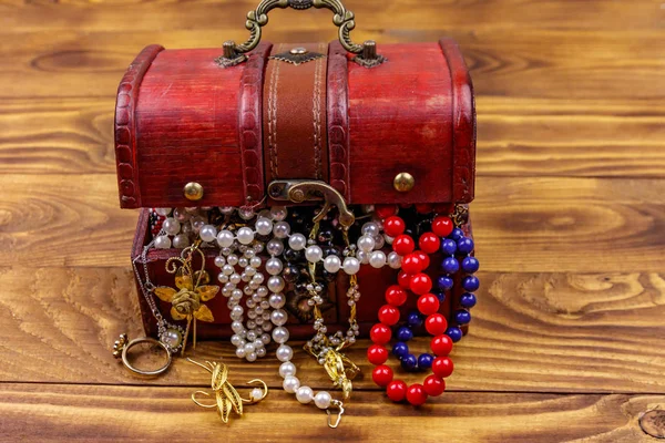 Vintage treasure chest full of jewelry and accessories on wooden background — Stock Photo, Image