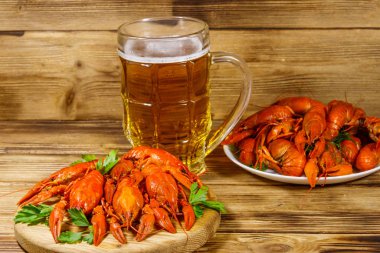 Haşlanmış kerevit ve bir kupa bira ahşap masada.