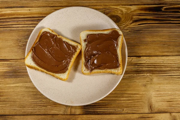 Twee sneetjes brood met heerlijke hazelnoot op houten tafel. Bovenaanzicht — Stockfoto