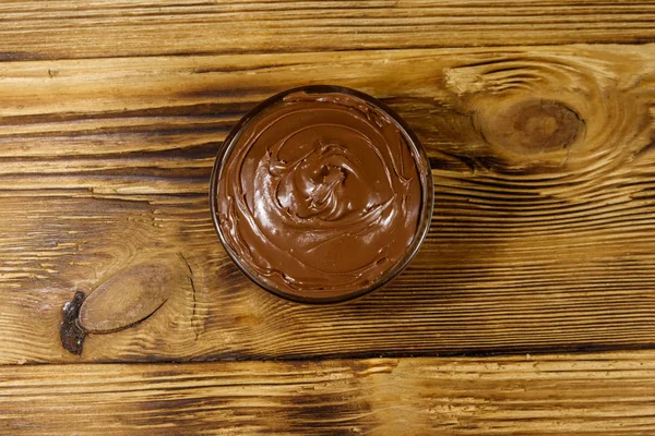Mangkuk kaca dengan hazelnut coklat lezat tersebar di atas meja kayu. Tampilan atas — Stok Foto