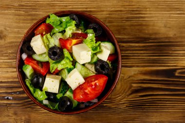Taze sebzeli Yunan salatası, beyaz peynir ve ahşap masada siyah zeytin. Üst görünüm