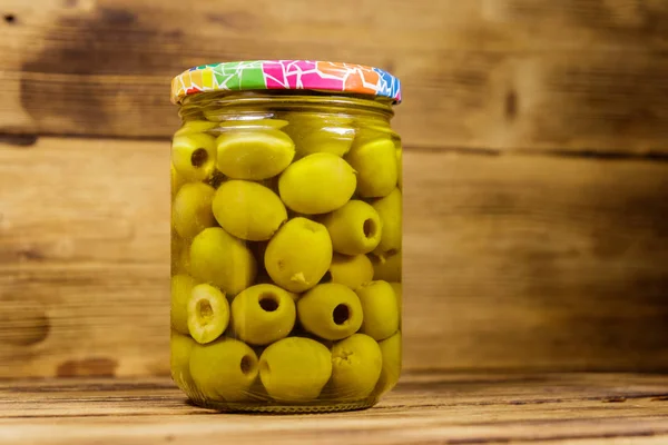 Aceitunas verdes en vinagre en frasco de vidrio sobre mesa de madera —  Fotos de Stock