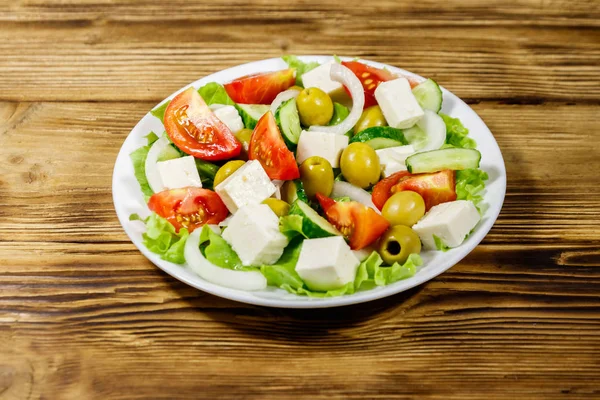 Griechischer Salat mit frischem Gemüse, Feta-Käse und grünen Oliven auf Holztisch — Stockfoto