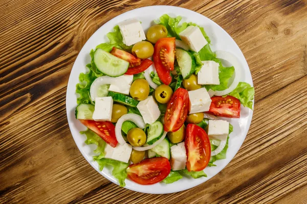 Salada grega com legumes frescos, queijo feta e azeitonas verdes em mesa de madeira. Vista superior — Fotografia de Stock