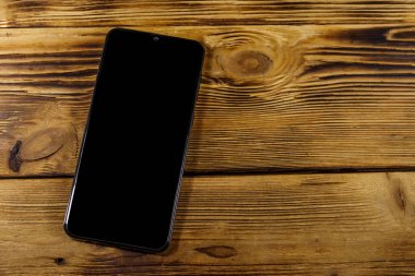 Kırsal ahşap bir masada modern akıllı telefon. Üst görünüm, alanı kopyala