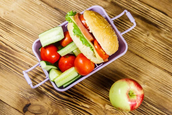 Scatola di mele e pranzo con hamburger e verdure fresche su un tavolo di legno. Vista dall'alto — Foto Stock