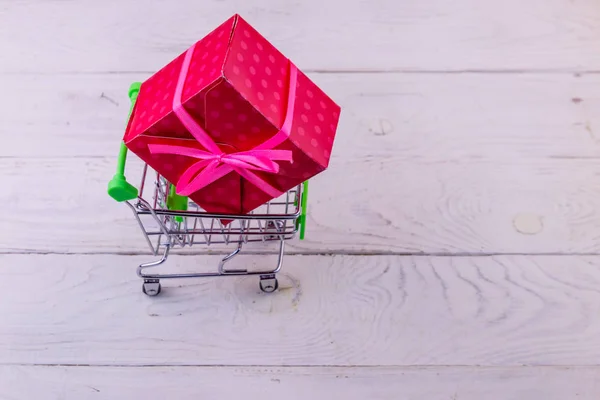 Carrito de compras con caja de regalo grande sobre fondo de madera blanco —  Fotos de Stock