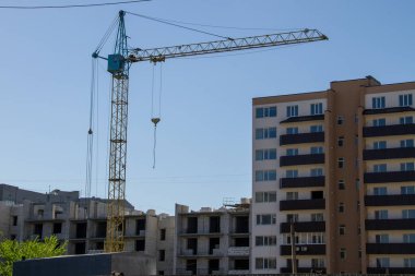 Mavi gökyüzüne karşı inşaat halindeki vinç ve bina