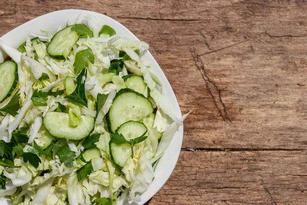 Tavaszi vegán saláta, káposzta, uborka, zöld hagyma, petrezselyem a fából készült asztal. Szemközti nézet — Stock Fotó