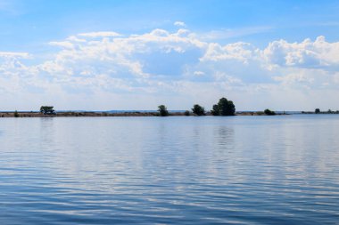 Güzel gölü, yeşil ağaçları ve mavi gökyüzü olan yaz manzarası.