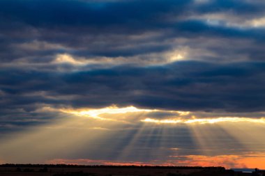 Kara bulutlarda parlayan ışınlar. Kara bulut ve ışık, ağzı açık kızgın bir yüz ve gözleri olan kızgın bir yüze benziyor.