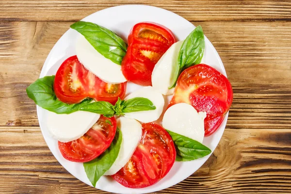 Salade de caprese italienne avec tomates, fromage mozzarella et basilic sur une table en bois. Vue du dessus — Photo