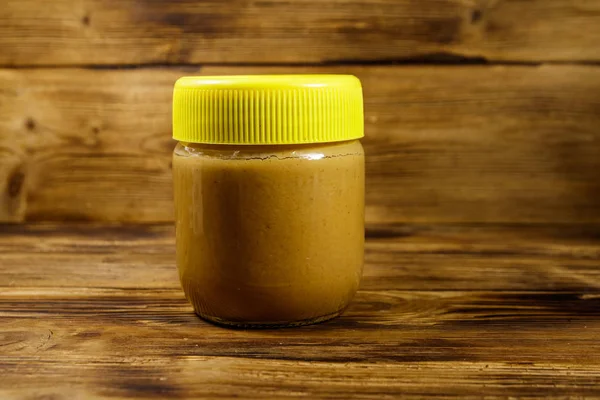 Банка арахисового масла на деревянном столе — стоковое фото