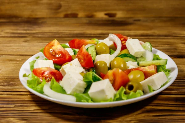 Греческий салат со свежими овощами, сыром фета и оливками на деревянном столе — стоковое фото