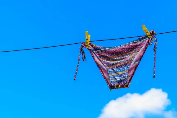 Сушка жіночого купальника, що висить на мотузці на блакитному небі — стокове фото
