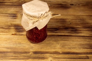 Ahşap masa üzerinde cam kavanozda ahududu reçeli