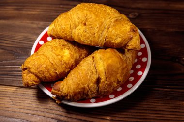 Ahşap masa üzerinde taze kruvasan ile Plaka