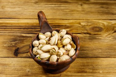 Tahta bir masada seramik kasede fıstıklar.