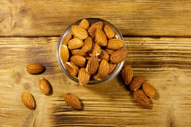 Kırsal ahşap bir masada cam kasede badem. Üst görünüm