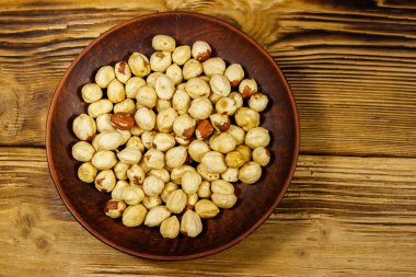 Ahşap masada seramik tabakta soyulmuş fındık. Üst görünüm