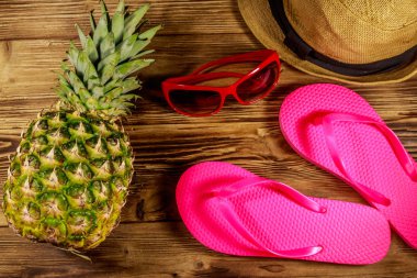 Yaz tatili konsepti. Ahşap arka planda ananas, hasır şapka, parmak arası terlik ve güneş gözlüğü