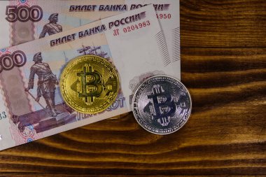 Ahşap arka planda altın ve gümüş Bitcoins ve 500 Rus ruble faturaları