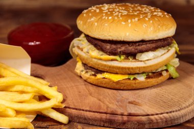 Tahta masada patates kızartması ve ketçaplı leziz büyük hamburger.