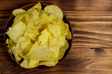 Tahta masada bir tabak patates cipsi. Üst görünüm