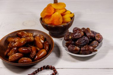 Kurumuş kayısılar ve beyaz ahşap masada ahşap tespihli meyveler. Müslümanların kutsal Ramazan bayramı