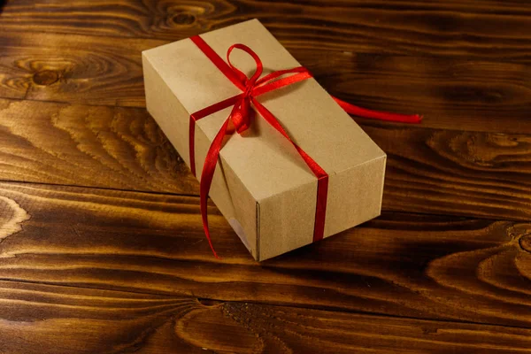 Χάρτινο Κουτί Δώρου Κόκκινη Κορδέλα Ξύλινο Τραπέζι — Φωτογραφία Αρχείου