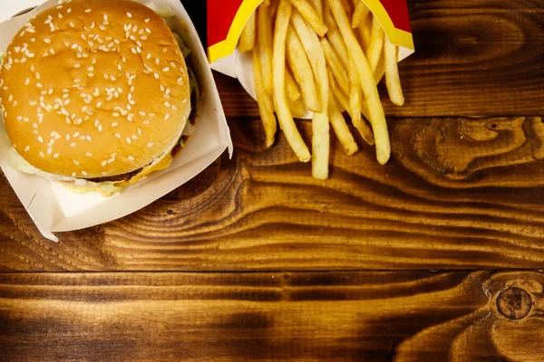 大きなハンバーガーと木製のテーブルの上にフライドポテト トップビュー コピースペース — ストック写真