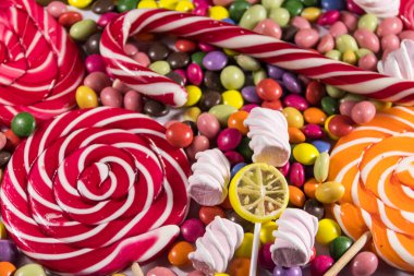Renkli çikolata şekerlemeleri, lolipoplar, şeker kamışı ve şekerlemelerin arka planı