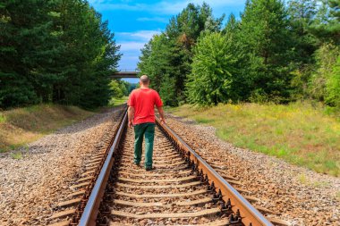 Yalnız adam tren yolunda yürüyor.
