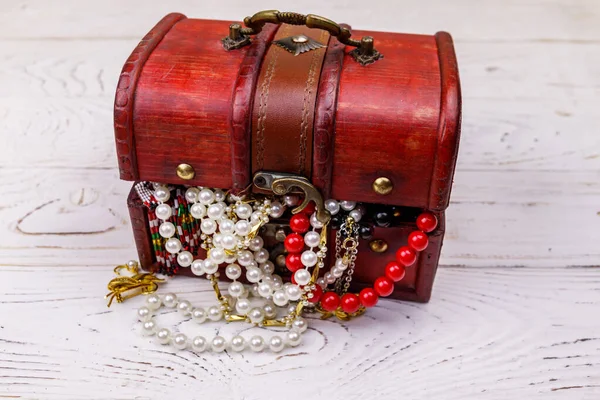 Vintage treasure chest full of jewelry and accessories on white wooden background