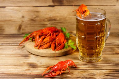 Haşlanmış kerevit ve bir kupa bira ahşap masada.